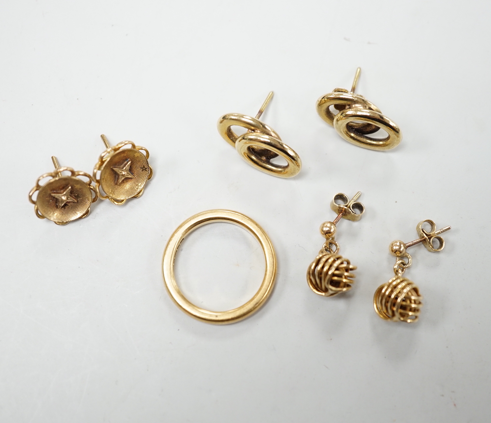An 18ct gold wedding band, size L/M, 5.2 grams and three pairs of yellow metal earrings.